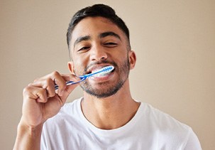 Man brushing teeth with white and blue brush