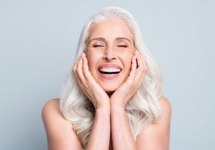 Woman with white hair cupping her face smiling