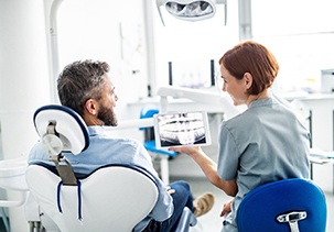 Dentist reviewing X-ray with smiling patient